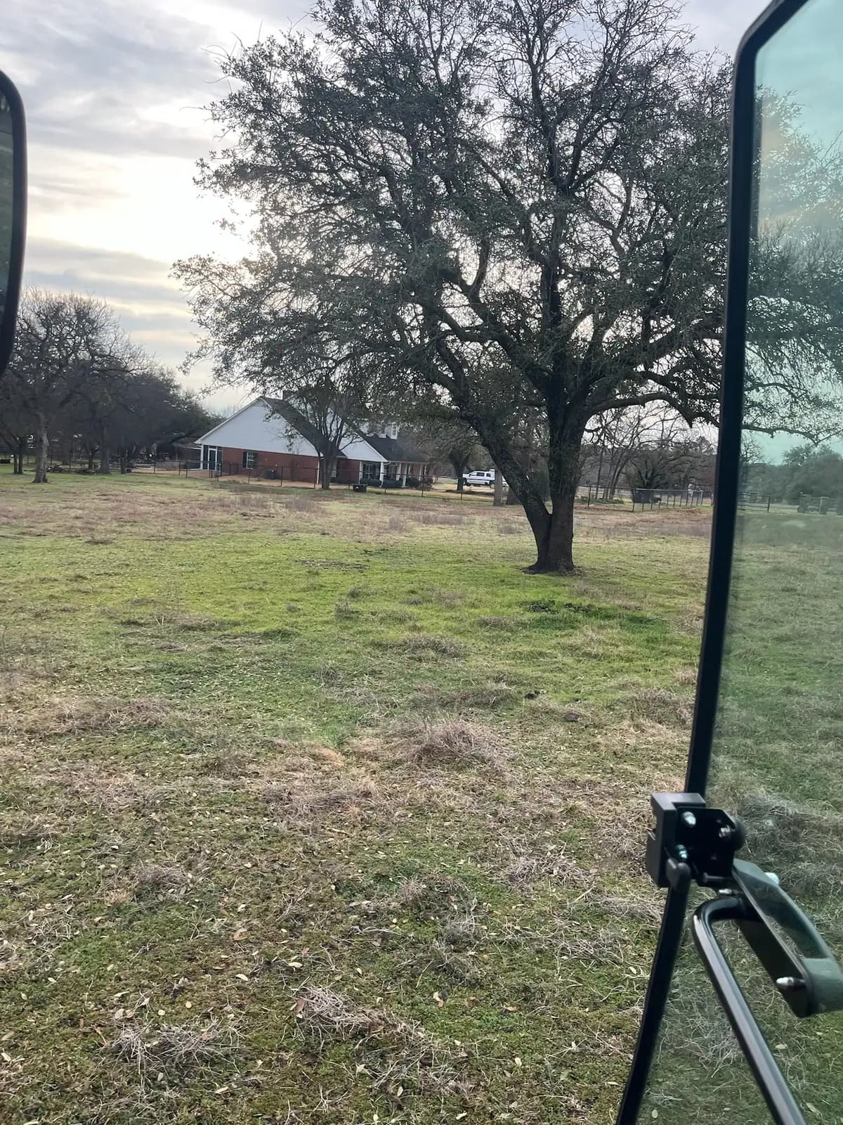 Brush hog mowing a pasture under mature oaks with a red tractor near Granbury, TX