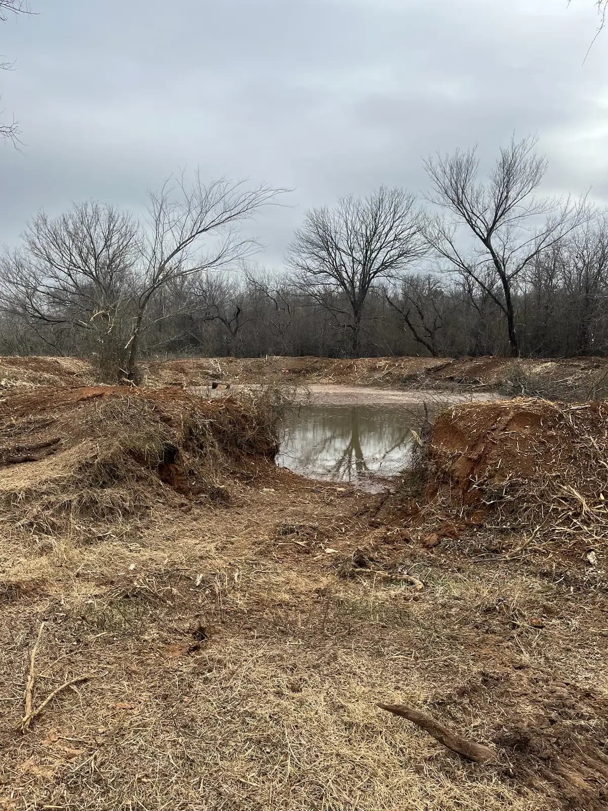 Stock pond banks cleared of brush and reshaped on a ranch near Granbury, TX